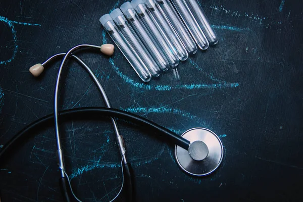 concept of medical diagnosis and therapy, stethoscope and test tubes on a dark background