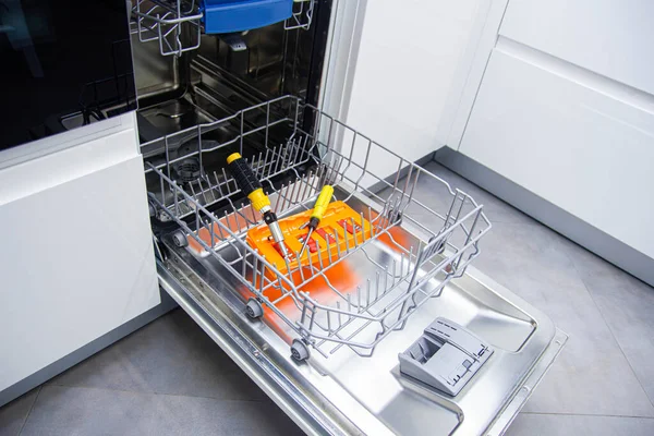 repair of a modern dishwasher with screwdrivers in the kitchen