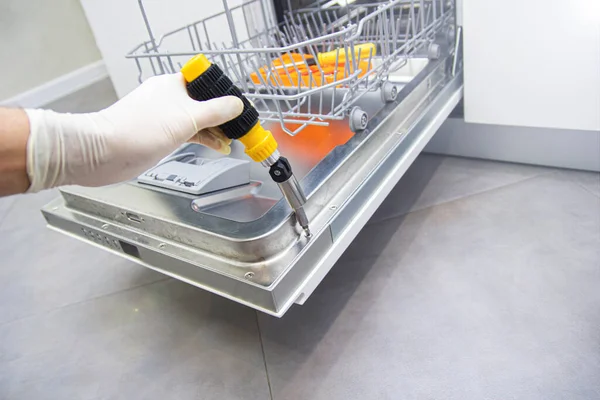 repair of a modern dishwasher with screwdrivers in the kitchen