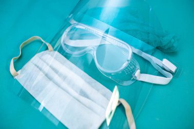 Mavi arka planda doktor, yüz kalkanı, gözlük ve maske için tıbbi koruyucu ekipman.