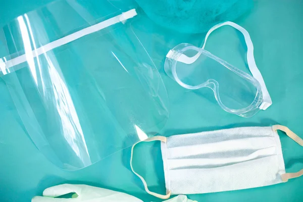 medical protective equipment for doctor, face shield, glasses and mask on a blue background.