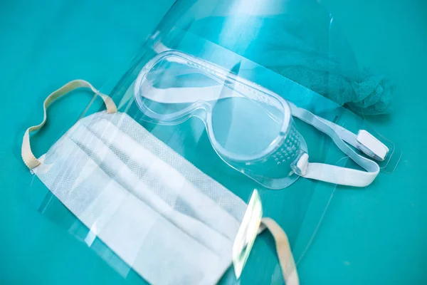 medical protective equipment for doctor, face shield, glasses and mask on a blue background.