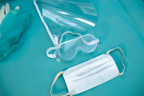 medical protective equipment for doctor, face shield, glasses and mask on a blue background.