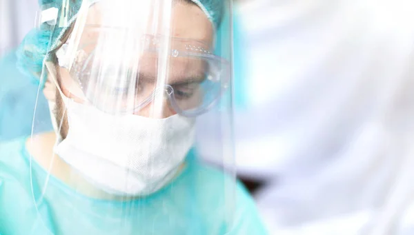 外科医は眼鏡と保護シールドとマスクで 手術室で働く若い専門家 — ストック写真