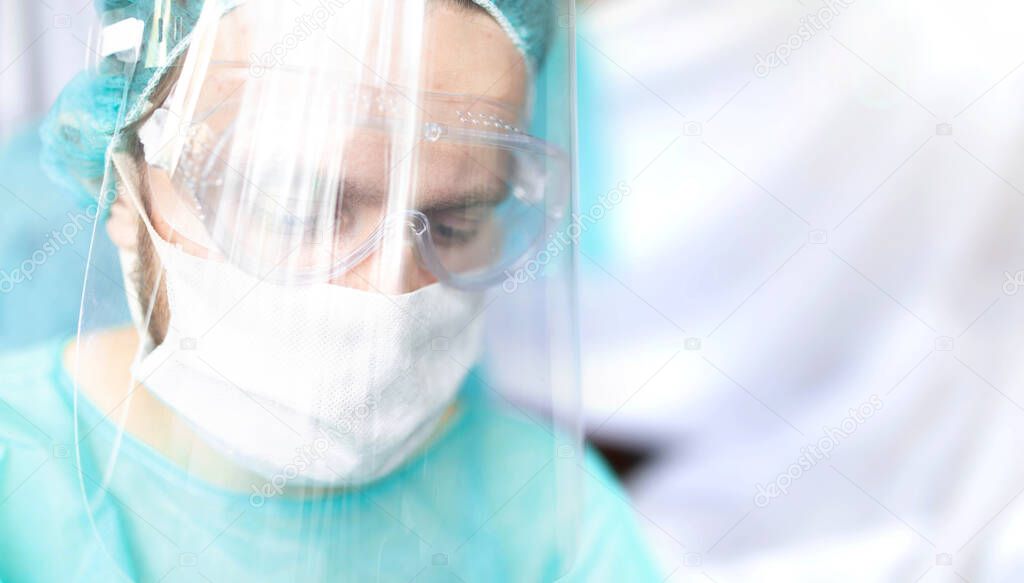 surgeon with glasses and a protective shield and mask. Young specialist works in the operating room