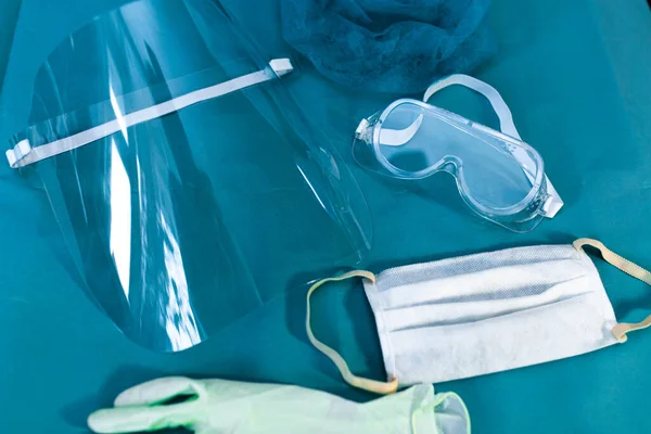 Mavi arka planda doktor, yüz kalkanı, gözlük ve maske için tıbbi koruyucu ekipman.