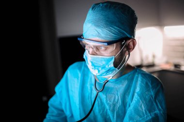Coronavirus salgını sırasında ameliyat odasında üniformalı ve gözlüklü genç cerrah..