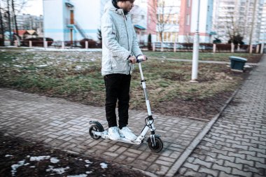 Soğuk bir kış gününde beyaz elektrikli scooter süren bir adam. Elektrik taşımacılığı.