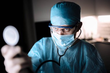 Coronavirus salgını sırasında ameliyat odasında üniformalı ve gözlüklü genç cerrah..
