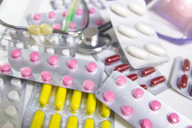 Renkli ilaç hapları ve steteskop seti, tıbbi teşhis ve terapi konsepti.