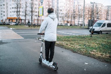 Soğuk bir kış gününde beyaz elektrikli scooter süren bir adam. Elektrik taşımacılığı.