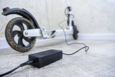 Yeni modern elektrikli scooter duvarın yanında şarj oluyor, yakın görüş 