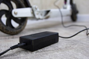 Yeni modern elektrikli scooter duvarın yanında şarj oluyor, yakın görüş 