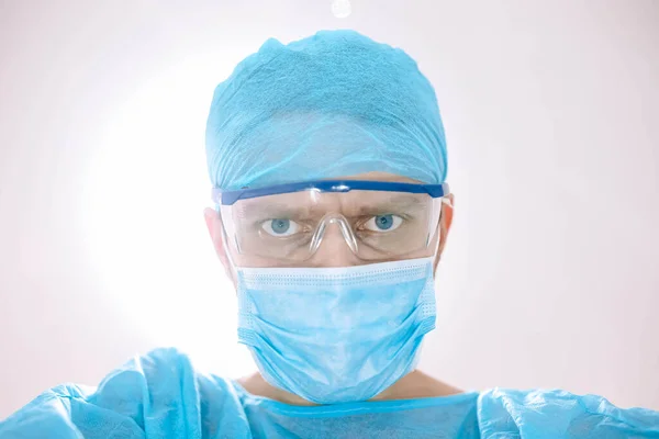 surgeon with glasses and protective mask working in operating room