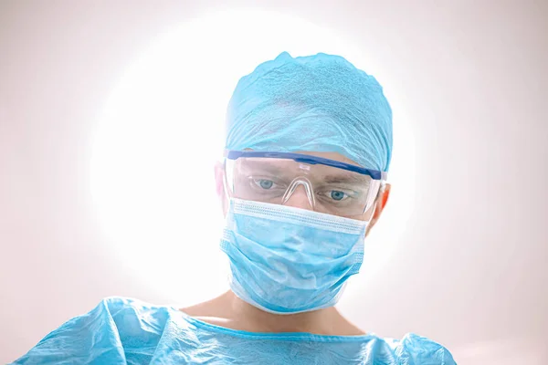 surgeon with glasses and protective mask working in operating room