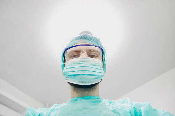 surgeon with glasses and protective mask working in operating room