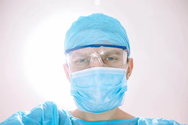 surgeon with glasses and protective mask working in operating room