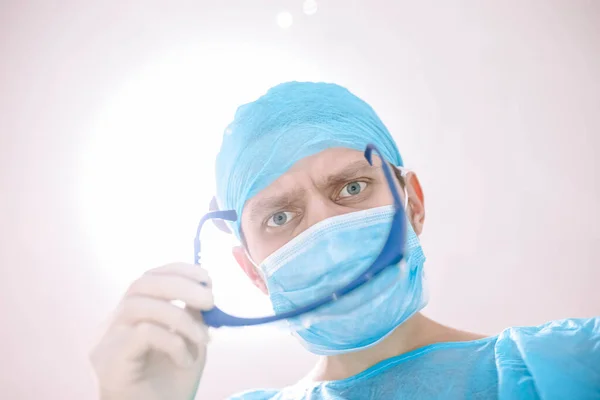 surgeon with glasses and protective mask working in operating room