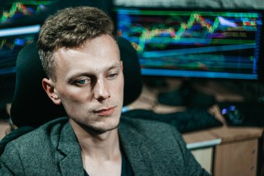 Genç Slav erkek hacker borsa ve çizelgeleri olan bir bilgisayar başında.