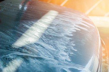 Mavi arabanın manuel oto yıkamada yakın çekimi.