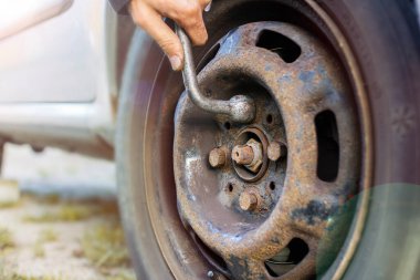 Bir adamın arabadaki tekerleği değiştirmesine, fındıkları İngiliz anahtarıyla gevşetmesine yakın çekim..