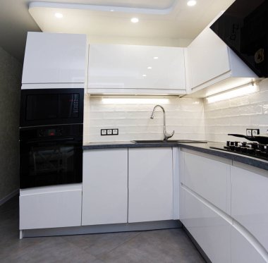 Dahili aletleri olan modern beyaz bir mutfak. Sıkıştırılmış minimalist mutfak