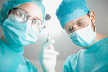 Hastane ameliyathanesinde genç bir asistanı olan profesyonel bir cerrah. Daha düşük bir açıdan vurulmuş, ameliyat.