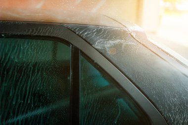 Mavi arabanın manuel oto yıkamada yakın çekimi.