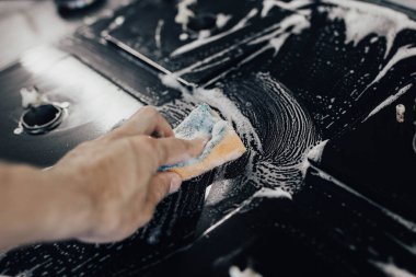 Mutfak konseptini temizlemek, kadın elinin sünger ve köpükle modern bir gaz sobasını temizlemesi.