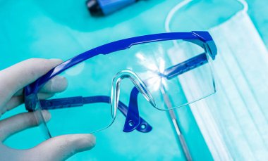 Doktor tıpta cerrahi koruyucu modern bardaklar tutuyor.