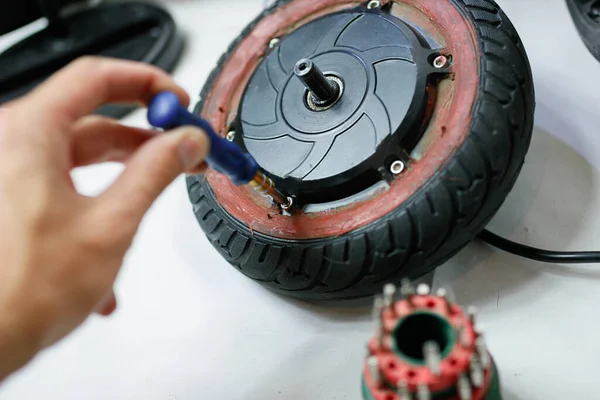 Man holding scooter wheel at electric motor repair service. Eco-friendly electric vehicle repair service