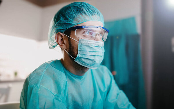 surgeon in uniform is working with a computer in a medical office, training doctors.