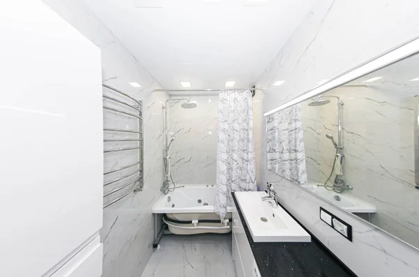 interior of a modern bathroom, heated towel rail, sink and ceramic tiles - imitation of marble.