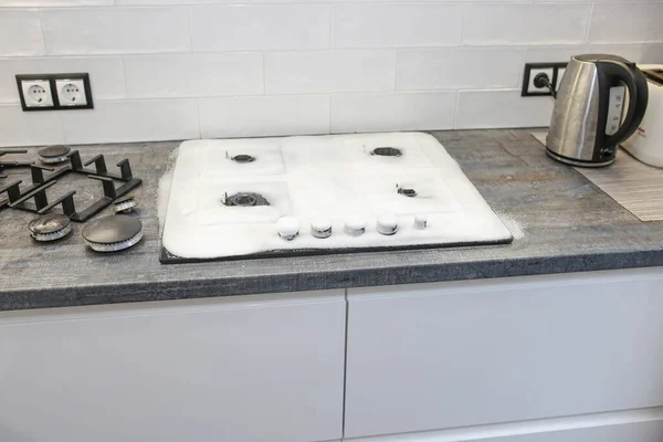 Cleaning the kitchen, cleaning a modern gas stove with a sponge and foam