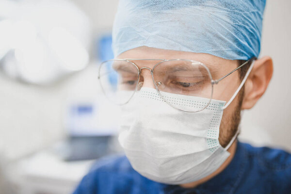 Thoughtful look of male doctor in uniform and glasses. Concept of hard work in medicine.