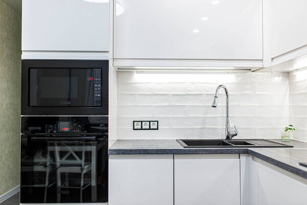 Interior of a modern white kitchen with built-in appliances. Compact minimalist kitchen