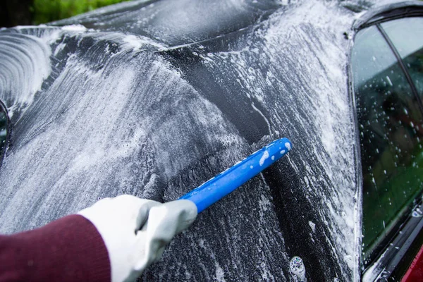 cleaning the tarpaulin roof of the convertible with foam cleaner.