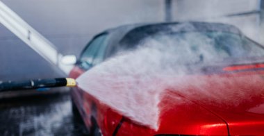 Kırmızı bir arabayı suyla kompresörle yıkamak..