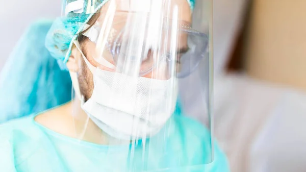 Medical surgeon in uniform and face shield in the operating room during a pandemic.
