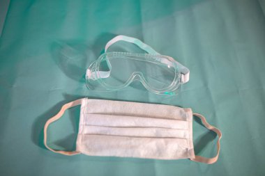Mavi arka planda koruyucu tıbbi gözlük ve maske..