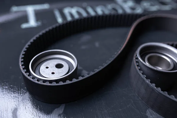 Timing belt and rollers with bearings on a black board.