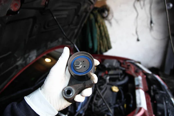 Car timing belt tensioner in hand of mechanic