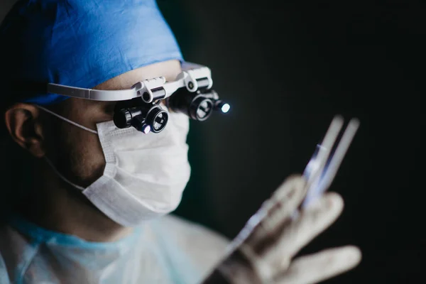 Chirurg Dalekohledem Zvětšovací Brýle Operuje Pacientovi Tmavém Operačním Sále — Stock fotografie