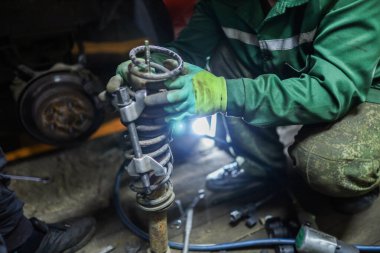 Otomatik mekanik, yayı şok emicinin yerine kablo bağıyla sıkıştırır. Araba süspansiyonu tamiri.