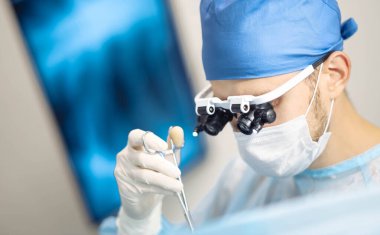 Erkek beyin cerrahı, modern bir ameliyathanede dürbün ve mikroskop mercekleriyle cerrahi aletler kullanır..