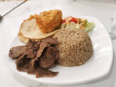 Yumuşak et dilimleri, yumuşak pirinç, taze salata ve lezzetli çıtır çıtır atıştırmalıklar içeren lezzetli bir donör kebap tabağı dengeli bir aşçılık deneyimi ve bir tabak kültürün tadını sunuyor..