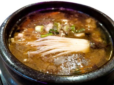 Bu Kore kâsesinin derin ve lezzetli lezzetlerinin tadını çıkarın, lezzetli bir soğan mantarı ve zengin et suyu karışımı, rahatlatıcı ve otantik bir deneyim için kırsal bir toprak kapında servis edilir..