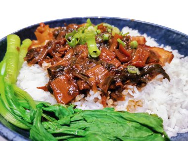 Yumuşak pirinçle servis edilen domuz pirincinin lezzeti. Bu mutfak başyapıtı taze yeşil sebzeler ve aromatik baharatlarla tamamlanır..