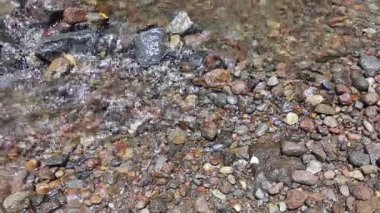 Sakin bir dere pürüzsüz, renkli nehir kayalarının üzerinden akar. Çıplak ayaklar serin, berrak suya batar, ferahlatıcı bir kaçış ve doğayla bağlantı sunar..