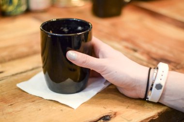 Siyah seramik kupa restoranda tutan kadın